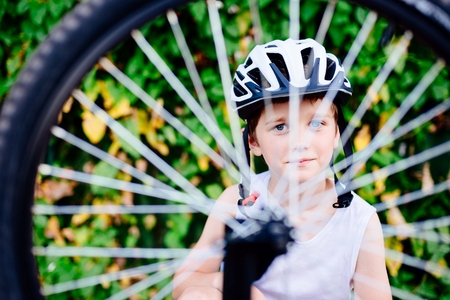 Happy boy in a bicycle helmet repairing his bike. Child on bikeの写真素材