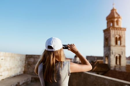 Woman tourist taking photo of old church with her smartphone. Dubrovnik, Croatiaの写真素材