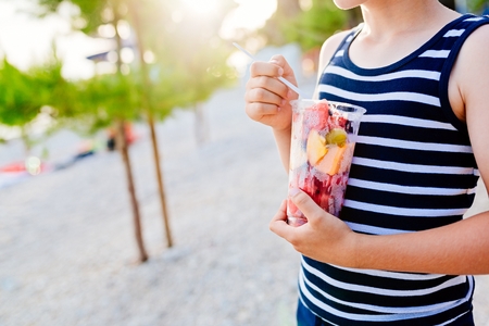 Child eating sliced fruits from plastic cup.の写真素材