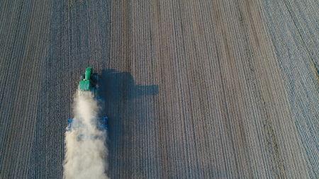Aerial view on tractor ploughing field. Summer farm worksの写真素材