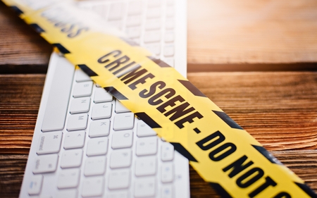 Yellow crime scene tape on computer keyboard. Computer crime concept.の写真素材