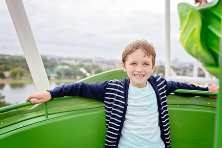Happy child boy having fun in amusement park. Taking a ride on ferris wheelの写真素材