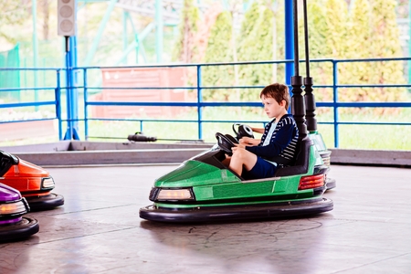Happy child boy having fun in amusement park. Taking a ride on bumper car.の写真素材