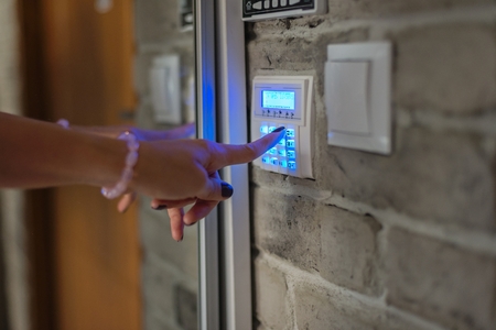 Home security system. Woman entering password on home alarm keypadの写真素材