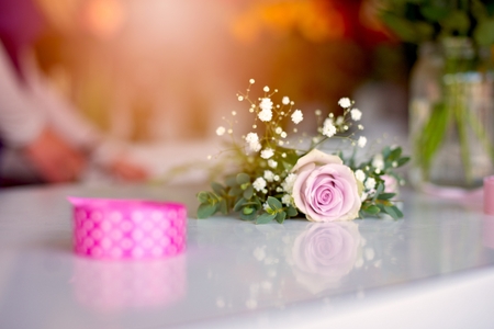 Woman owner of florist shop preparing bouquet of pink roses. Wearing blue apron. Small business conceptの写真素材