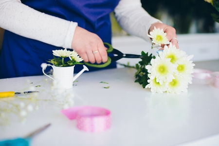 Florist woman making a miniature flower composition in small watering can. White gerbera daisies. Small business conceptの写真素材