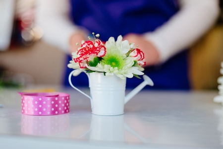 Florist woman making a miniature flower composition in small watering can. White gerbera daisies. Small business conceptの写真素材