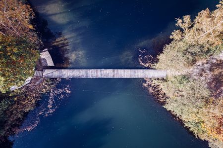 Aerial drone view on two little islands on the lake connected by small wooden bridge. Autumn at the lakeの写真素材