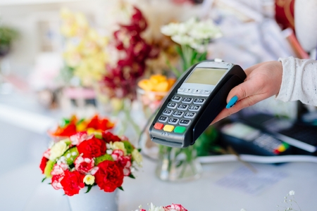 Credit card payment. Florist shop owner holding credit card terminal.の写真素材