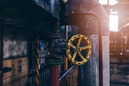 Old yellow valve and pipes in an old power plantの写真素材