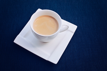 Freshly made coffee in a small white cup with saucerの写真素材