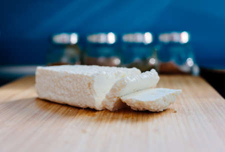 White healthy cottage cheese on wooden cutting board in the kitchenの写真素材