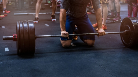 Close up on muscular man preparing to weightlifting in functional fitness gym.