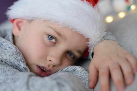 Tired child in Santa Claus hat lying in bed at Christmas. Merry Christmas !の写真素材