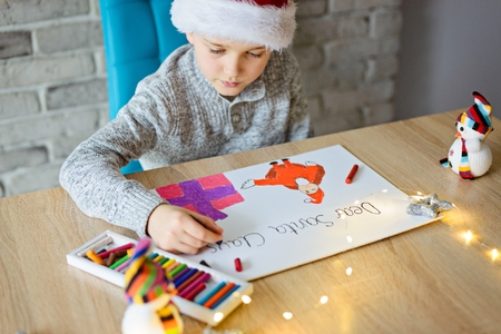 Boy drawing a pastel drawing of Santa Claus and present.の写真素材