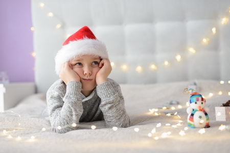 Boy in Santa Claus hat dreaming about Christmas. Merry Christmas !の写真素材