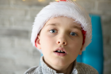 Close portrait of 8 years boy in Santa Claus hat at Christmasの写真素材