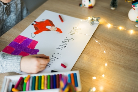 Child drawing a pastel drawing of Santa Claus and present.の写真素材