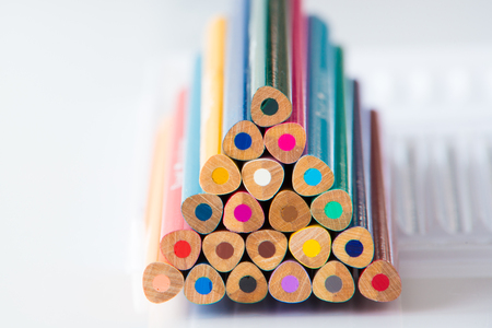 Stacked wooden coloured pencils on white background.の写真素材