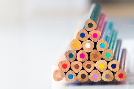 Stacked wooden coloured pencils on white background.の写真素材