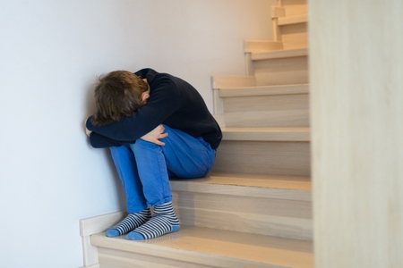 Sad crying child alone on home stairsの写真素材