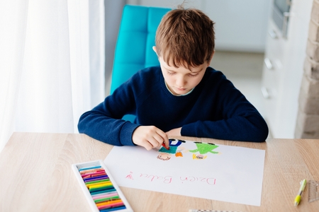 Happy Polish child drawing a greeting card for his grandma. Polish word Grandmother Day!の写真素材