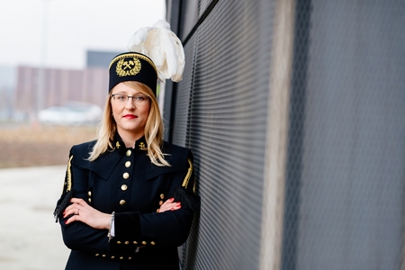 Woman black coal miner in gala uniform with white feathers on a mining hat. Working woman