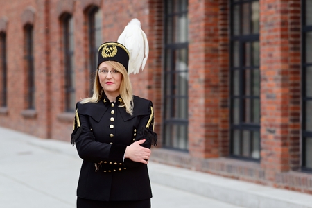 Woman black coal miner in gala uniform with white feathers on a mining hat. Working womanの写真素材