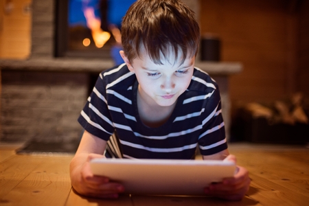 Eight years old boy using digital tablet at home.の写真素材