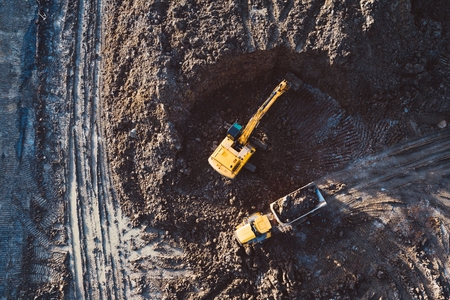 Aerial drone view of excavator loading the tipper truck at the construction siteの写真素材