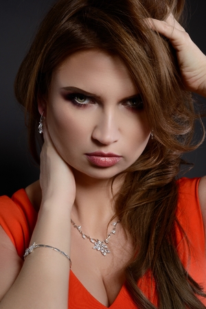 Studio beauty shot of woman with silver necklace and bracelet. Beautiful young woman posing with jewelry. Dark backgroundの写真素材
