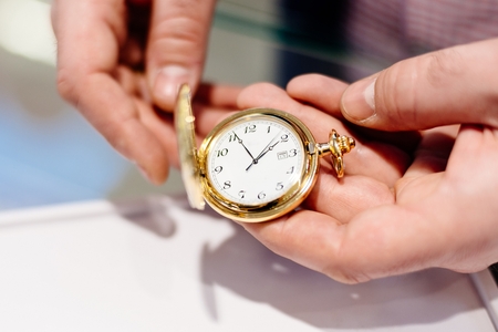 Man opens retro styled vintage gold coloured pocket watchの写真素材