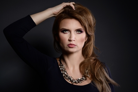 Studio beauty shot of woman with polished stone necklace. Beautiful young woman posing with jewelry. Dark backgroundの写真素材