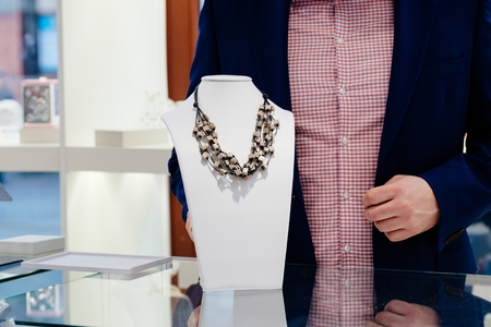 Polished stone necklace on neck stand display in a jewelry storeの写真素材