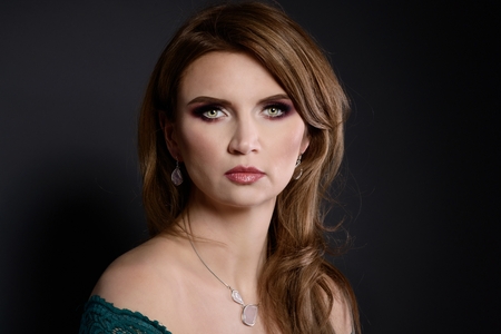 Studio beauty shot of woman with necklace. Beautiful young woman posing with jewelry. Dark backgroundの写真素材
