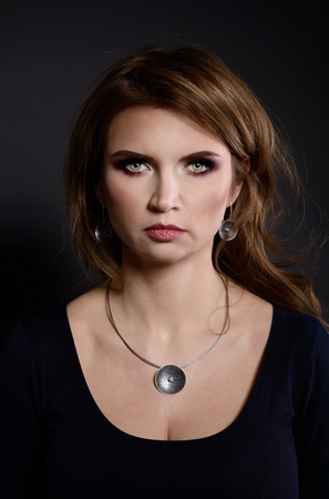 Studio beauty shot of woman with necklace. Beautiful young woman posing with jewelry. Dark backgroundの写真素材