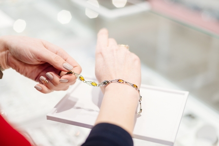 Woman owner of jewelry shop presenting silver bracelet with amber. Customer service in jewelry store.の写真素材