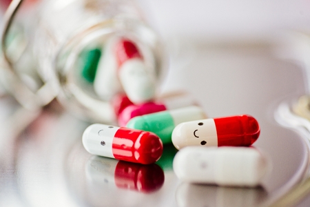 Capsule pills with smile on reflective surface.の写真素材