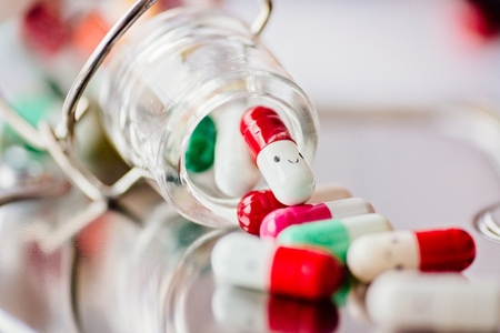 Capsule pills with smile on reflective surface.の写真素材