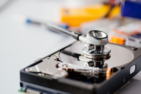 Hard disk drive health. Medical stethoscope on opened hard disk