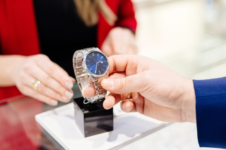 Young elegant man buying wrist watch in jewelry store. Customer service in jewelry storeの写真素材