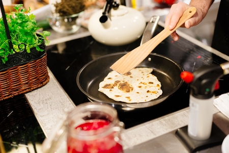 Woman frying tortilla wraps on frying pan in the kitchenの写真素材