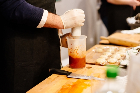 Man preparing and mixing with blender tomato pepper sauceの写真素材