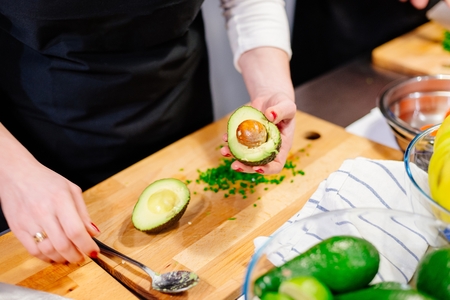 Woman cook opening avocado on the wooden cutting boardの写真素材