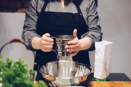 Woman cook sifting white flour to the bowl. Culinary workshopの写真素材