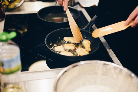 Woman frying breaded fish in hot oil on frying panの写真素材
