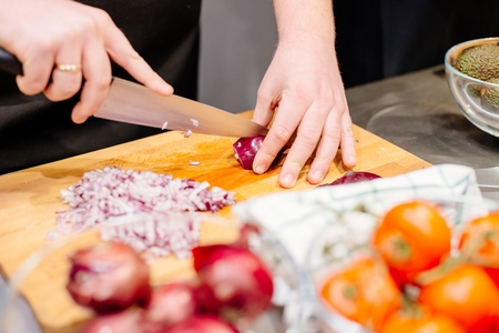Woman cook cutting red onion on the wooden cutting boardの写真素材