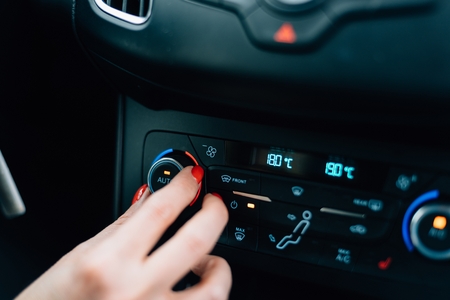 Woman regulating temperature on car air condition. Modern car interiorの写真素材