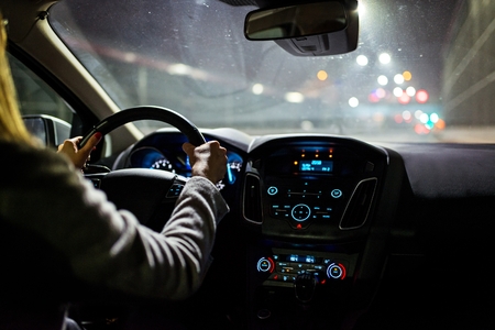 Young woman driving a car at night. Modern car interiorの写真素材