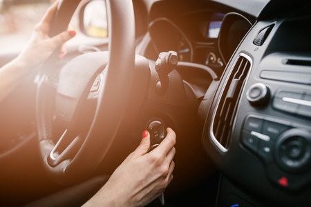 Young woman starting car engine with key. Modern car interiorの写真素材
